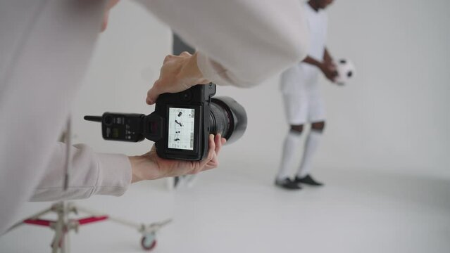 Photographer takes professional photos of a black football player in the studio on a white background