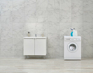 Washing machine and cabinet and sink in the white bathroom, cleaning materials, dirty clothes in the basket style.