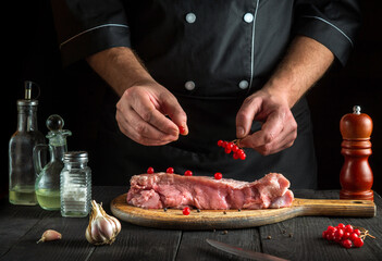 Professional  cook prepares raw veal meat. Before baking, the chef puts the viburnum on the beef. National dish is being prepared in the kitchen