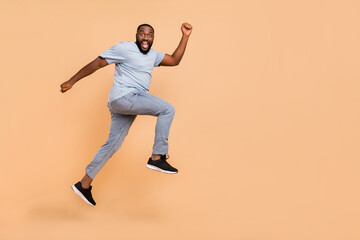 Fototapeta na wymiar Full length body size view of attractive cheerful sportive guy jumping striving isolated over beige pastel color background