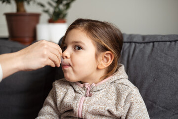 Caucasian girl portrait taking bronchitis treatment from dosage spoon at home