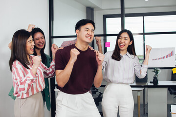 Obraz premium Asian young business man and his colleagues wearing casual shirt is smiling and very happy with his success in office. Working, Teamwork and Leadership Concept.