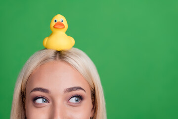 Cropped photo of curious lady look empty space think rubber duck up head wear striped overall isolated green color background