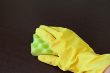 Female hand in yellow household glove wipes washes table