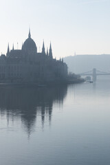 Parliament building and Szechenyi chain bridge in morning haze in Budapest, Hungary
