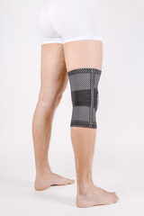 Knee Support Brace on leg isolated on white background. Elastic orthopedic orthosis. Anatomic...