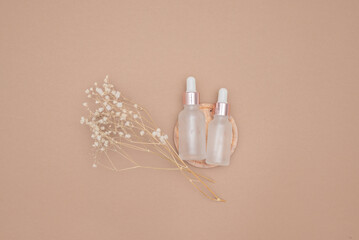 Glass dropper bottles on a beige background cast shadows. Top view, place for text.