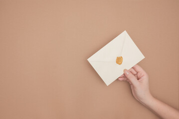 Close-up photo of female hands with wax seal with invitation envelope, gift certificate, postcard, wedding invitation card.