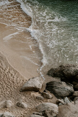 Relaxing scene at a holiday lounge deck by the sea overlooking blue waves and ocean, sun reflecting in water, blue sky and rocks in the background