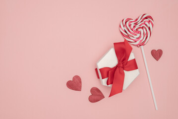Presents with red bow on pink background with hearts. Flat lay style. Valentine day concept