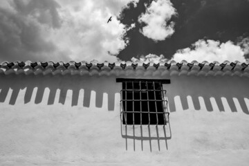 Black and white window with bars and shadows. Flying bird in the sky. Alhama de Granada, Andalusia, Spain.
Beautiful and interesting travel destination in the warm Southern region. Public street view.