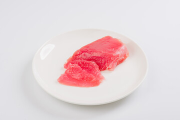 a piece of fresh tuna on a white plate on a white background