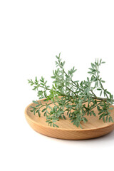 common rue leaves on a wooden plate, also known as ruta or herb of grace or garden rue, ruta graveolens, aromatic herbal foliage isolated on white background
