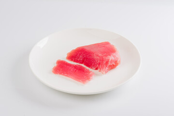 a piece of fresh tuna on a white plate on a white background