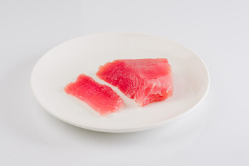 a piece of fresh tuna on a white plate on a white background