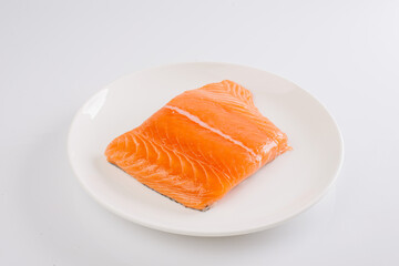 raw salmon fillet on a white plate on a white background