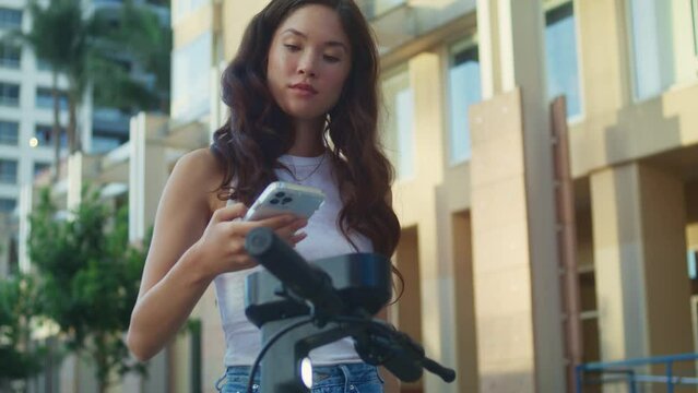 Asian lady rent scooter pay using smartphone close up. Woman take electric bike
