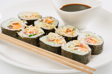 Sushi with chopsticks on a white plate. Sushi roll japanese food in restaurant isolated on white background. Fresh hosomaki pieces with rice and nori.