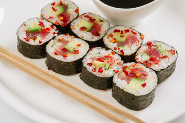 Sushi with chopsticks on a white plate. Sushi roll japanese food in restaurant isolated on white background. Fresh hosomaki pieces with rice and nori.