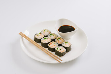 Sushi with chopsticks on a white plate. Sushi roll japanese food in restaurant isolated on white background. Fresh hosomaki pieces with rice and nori.