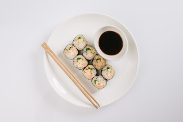 Sushi with chopsticks on a white plate. Sushi roll japanese food in restaurant isolated on white background. Fresh hosomaki pieces with rice and nori.