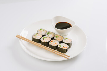 Sushi with chopsticks on a white plate. Sushi roll japanese food in restaurant isolated on white background. Fresh hosomaki pieces with rice and nori.