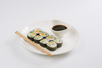 Sushi with chopsticks on a white plate. Sushi roll japanese food in restaurant isolated on white background. Fresh hosomaki pieces with rice and nori.