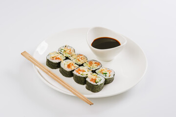 Sushi with chopsticks on a white plate. Sushi roll japanese food in restaurant isolated on white background. Fresh hosomaki pieces with rice and nori.