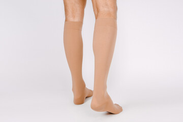 Medical Compression Stockings for varicose veins and venouse therapy. Compression Hosiery. Sock for sports isolated on white background. Beige color socks mock up for advertising, branding, design. - obrazy, fototapety, plakaty