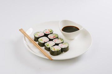 Sushi with chopsticks on a white plate. Sushi roll japanese food in restaurant isolated on white background. Fresh hosomaki pieces with rice and nori.