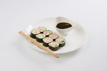 Sushi with chopsticks on a white plate. Sushi roll japanese food in restaurant isolated on white background. Fresh hosomaki pieces with rice and nori.