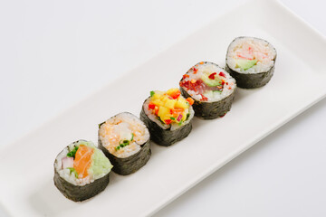 Sushi with chopsticks on a white plate. Sushi roll japanese food in restaurant isolated on white background. Fresh hosomaki pieces with rice and nori.