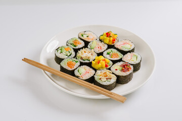 Sushi with chopsticks on a white plate. Sushi roll japanese food in restaurant isolated on white background. Fresh hosomaki pieces with rice and nori.