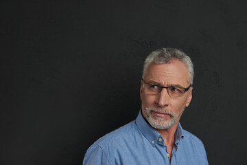 Concentrated senior man in glasses looking away