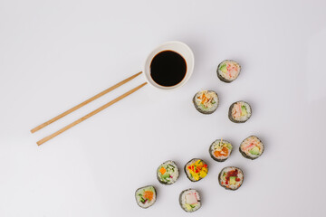 Fototapeta na wymiar Maki Sushi Rolls set on wooden board. Japanese traditional Cuisine. White background.