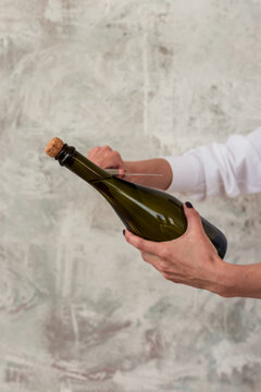 Sabre Wine. A Woman's Hand Opens A Bottle Of Champagne With A Knife. Gray Background. Place For Text