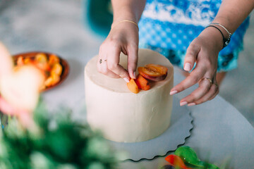 the girl cooks cakes in a beautiful bright kitchen. chef girl cooks chocolate cake with strawberries. the pastry chef puts the berries on the cake