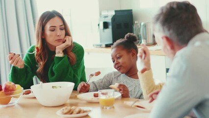 Cheerful multinational family eating breakfast at home
