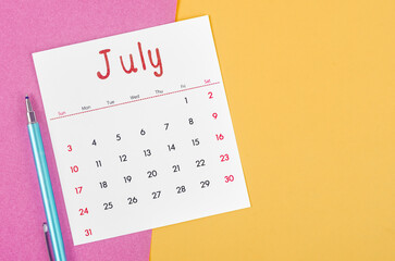 July 2022 calendar  with pen on multicolored background.