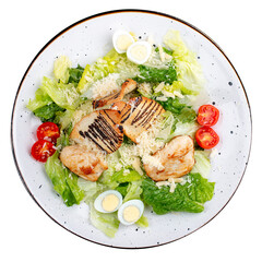 Caesar salad with chicken on a white decorative plate. A classic salad. Top view