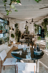 A rustic outdoor dining setup in Ibiza, featuring a shaded seating area with white wooden furniture under a canopy. Surrounded by olive trees, this cozy spot blends nature and Mediterranean charm