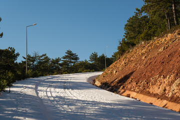 Bending mountain road with snow among the pine trees.
