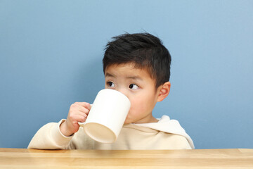 マグカップでドリンクを飲んでいる男の子。