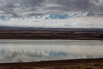 amazing mountains under grey clouds and reflection in mountain lake