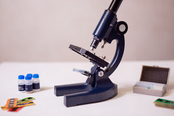 A schoolgirl with a microscope examines chemicals in test tubes, conducts experiments. The concept of coronavirus research in the laboratory