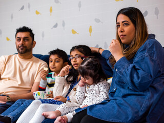 Parents with children sitting on sofa and watching TV