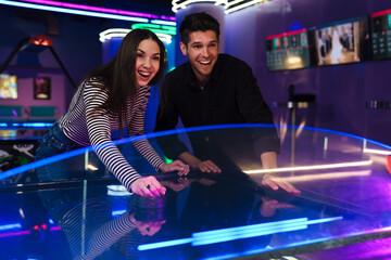 Fototapeta na wymiar White young friends laughing while playing air hockey