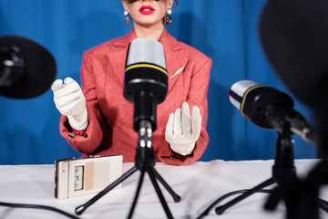 microphones near cropped vintage style woman giving interview on blue background