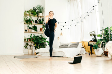 Young woman practicing yoga indoor, watch tutorial.