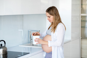 A pregnant woman cooks food in the kitchen.